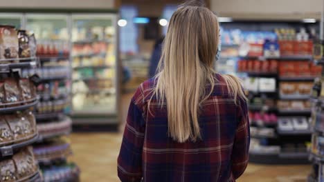 mujer joven lleva un carro con comestibles en el supermercado durante el período de cuarentena