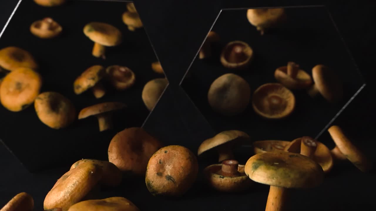 Funghi lattari arancioni freschi fluttuano su riflessi scuri da studio, con geometria speculare e toni caldi che creano un'atmosfera artistica e gourmet.