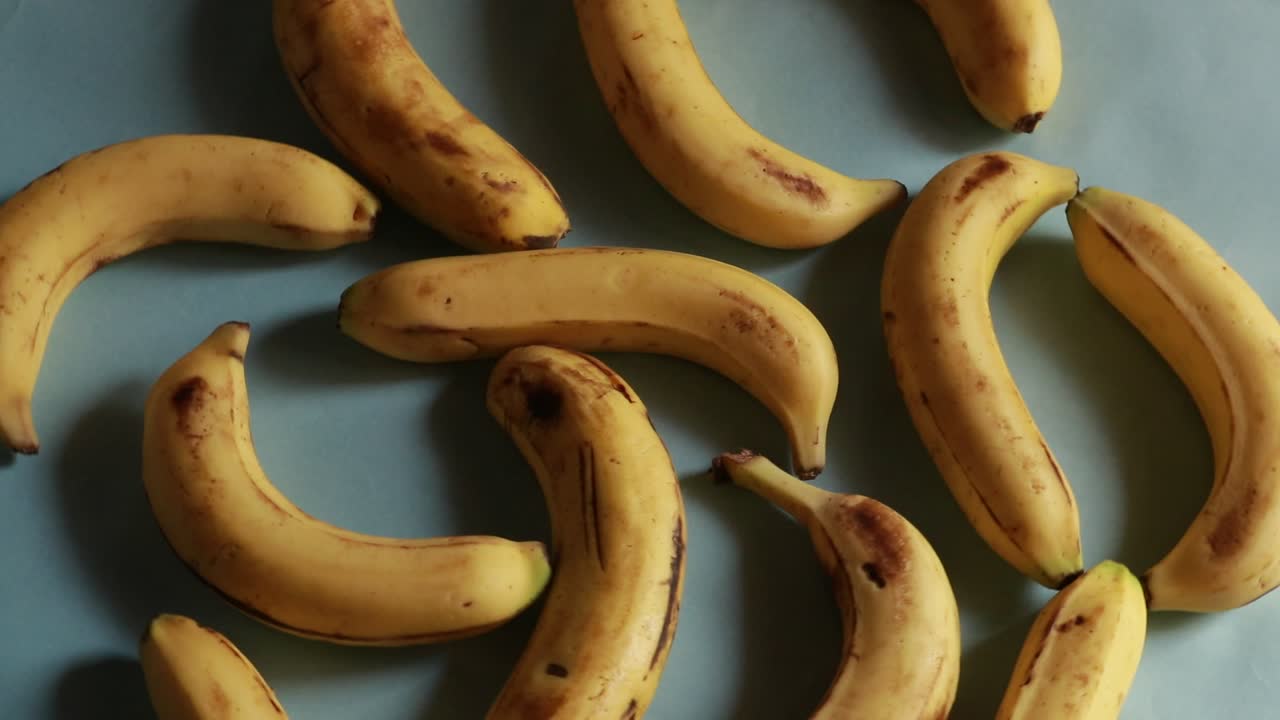 una foto macro de plátanos orgánicos amarillos maduros girando contra el fondo verde