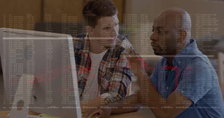 Two coworkers sitting at table, left man typing and bringing terminal overlay on monitor, debugging