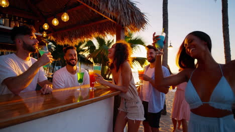 friends enjoying cocktails at a beach bar at sunset