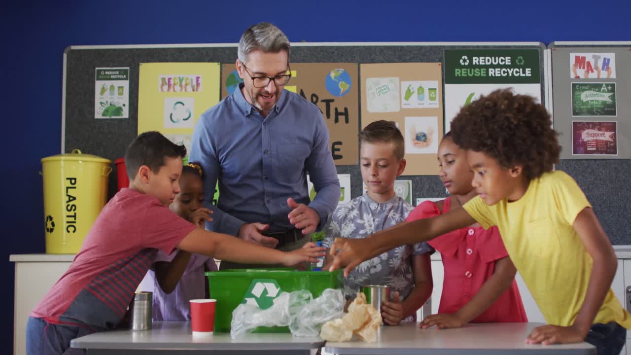 Diverse teacher and schoolchildren standing in classroom learning about ...