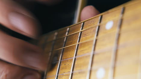 person beats metal nylon strings of brown acoustic guitar