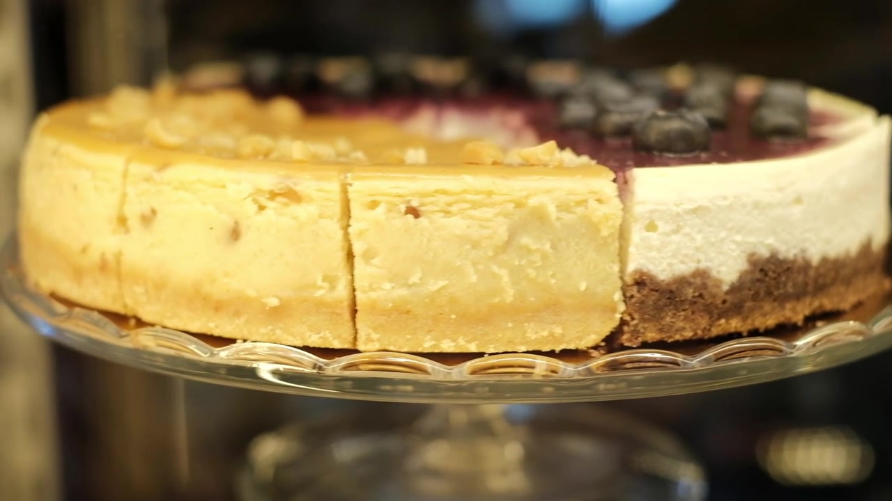 Plano de encerramento deslizante da direita para a esquerda de cheesecakes doces e frutados na vitrine da confeitaria