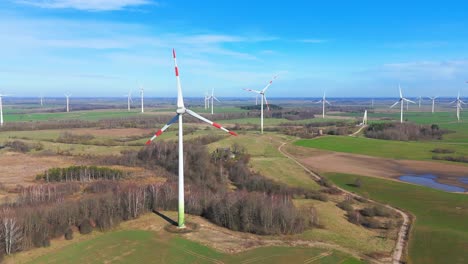 Drone-shot-of-energy-producing-wind-turbines-in-a-vast-field-on-a-sunny-day-in-Taurage,-Lithuania