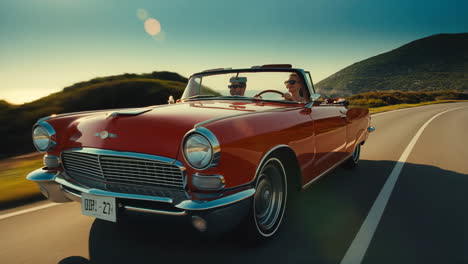 couple driving red convertible on scenic coastal road at sunset