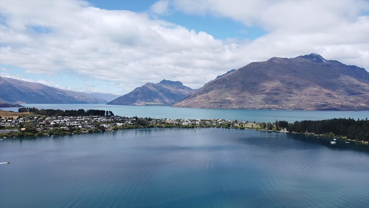 lapso de tiempo del lago wakatipu en el aire que muestra la ciudad de las casas de la isla y un taxi acuático en un bote a reacción conduciendo a través