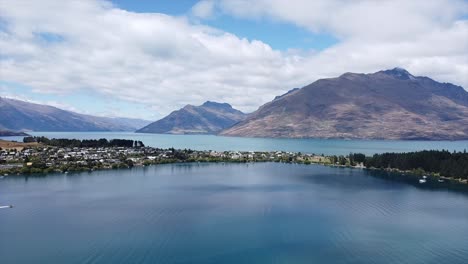 Lapso-De-Tiempo-Del-Lago-Wakatipu-En-El-Aire-Que-Muestra-La-Ciudad-De-Las-Casas-De-La-Isla-Y-Un-Taxi-Acuático-En-Un-Bote-A-Reacción-Conduciendo-A-Través