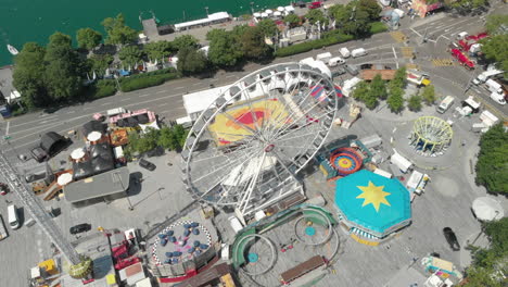 Hermoso-Dron-Aéreo-En-órbita-Volando-Hacia-Abajo-Y-Alrededor-De-La-Rueda-De-La-Fortuna-Del-Parque-De-Diversiones-Con-La-Ciudad-De-Zúrich,-Suiza-En-El-Fondo-Durante-Zürichfest-60fps