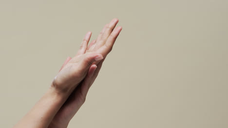 hands of asian woman on beige background with copy space, slow motion