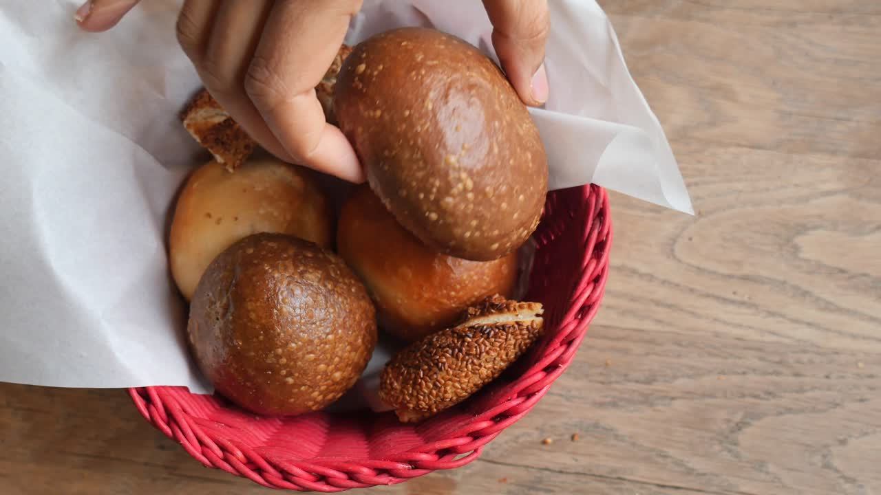Hand Taking a Fresh Bread Roll from a Basket
