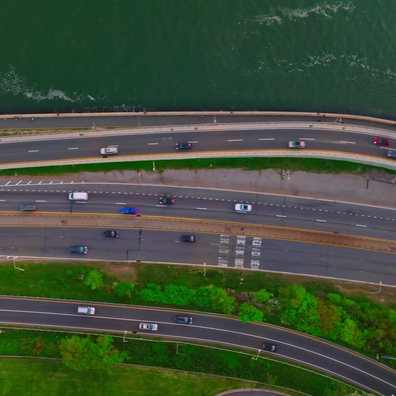 Few roads going through the green bank of the river. Aerial perspective on the motorways and cars going on