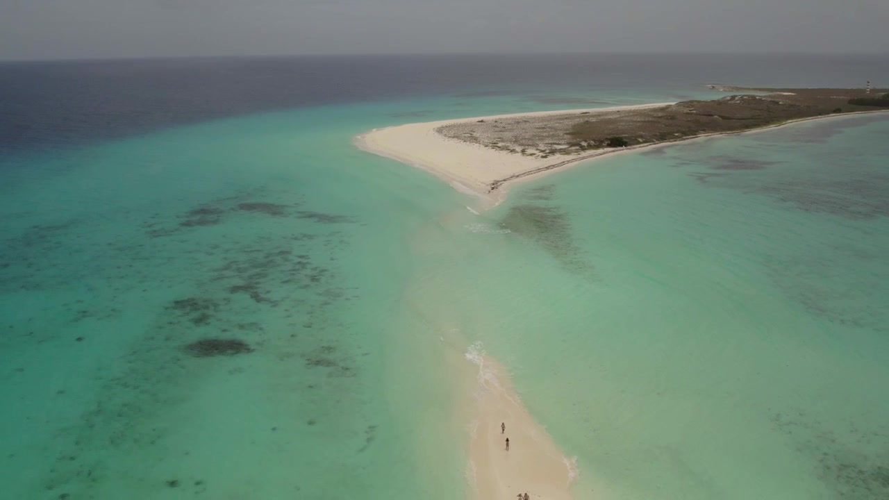 Luftfoto af mennesker, der går og slapper af på en sandbanke i turkist vand