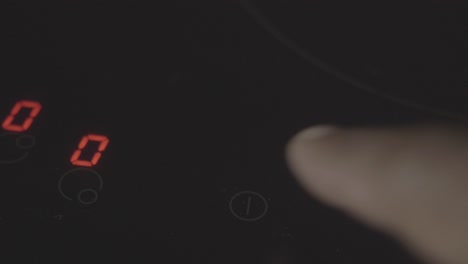 close-up of an electric stovetop with finger touching the controls