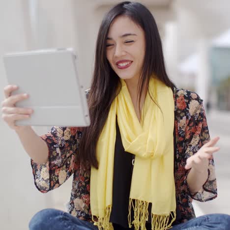 smiling woman waving at her tablet computer