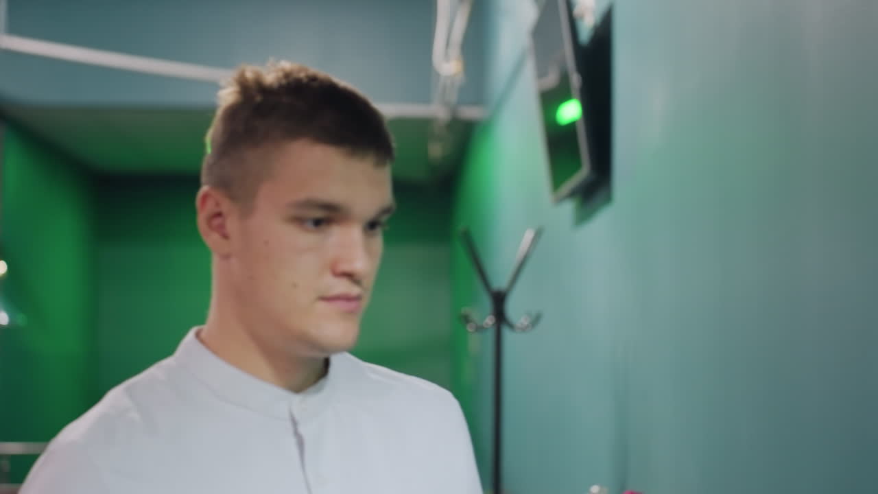 крупный план игрока в бильярд в белой рубашке, идущего к стойке для бильярдных шаров, берущего белый кубик. зеленое освещение, сфокусированное выражение, современная обстановка бильярдного зала, воздушные лампы, стильная атмосфера