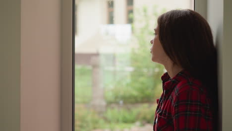 una mujer joven mirando por la ventana.