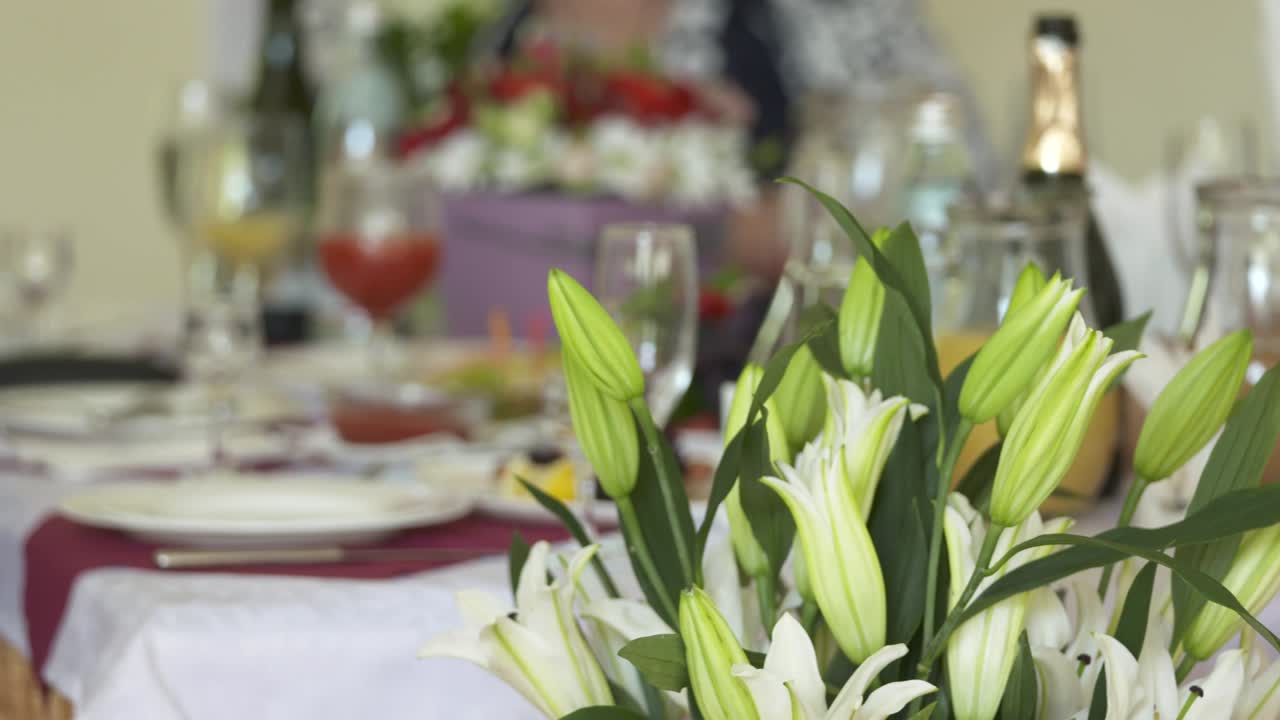 mesa de cena festiva decorada con arreglos florales de lirios y rosas