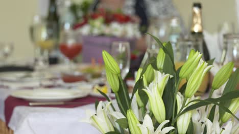 festive dinner table decorated with flower arrangements of lilies and roses