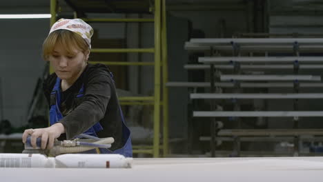 woman sanding wood in a factory