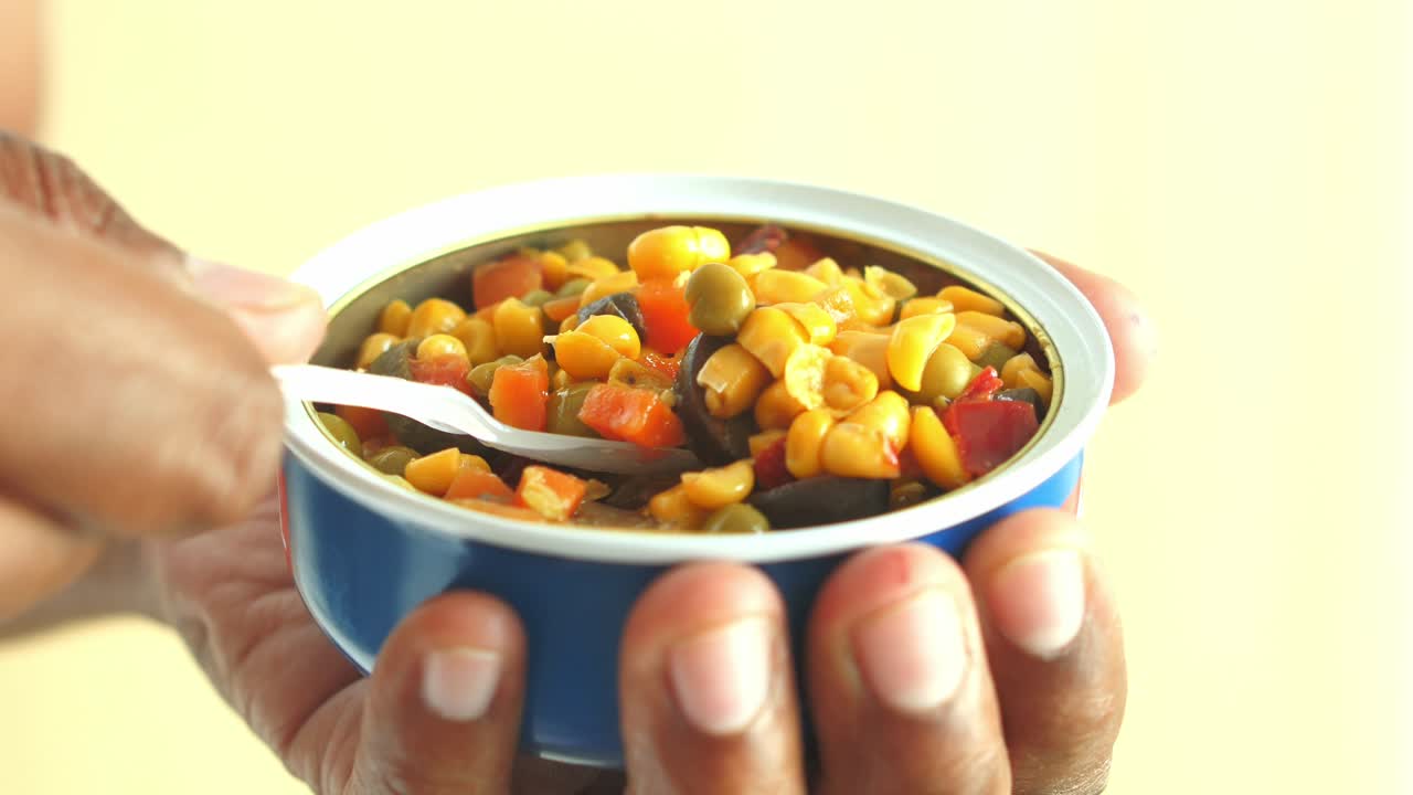 persona comiendo una lata de verduras mixtas