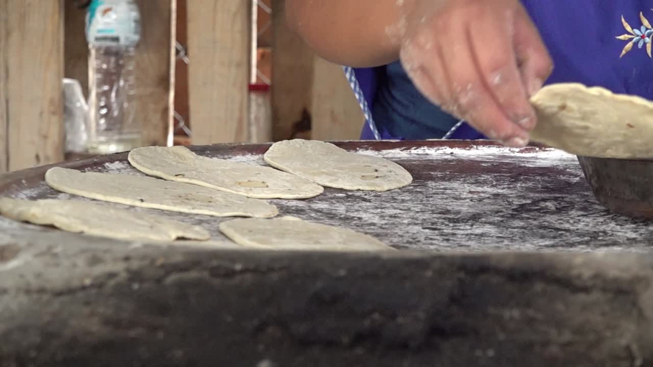 una mujer volteando tortillas en un comal