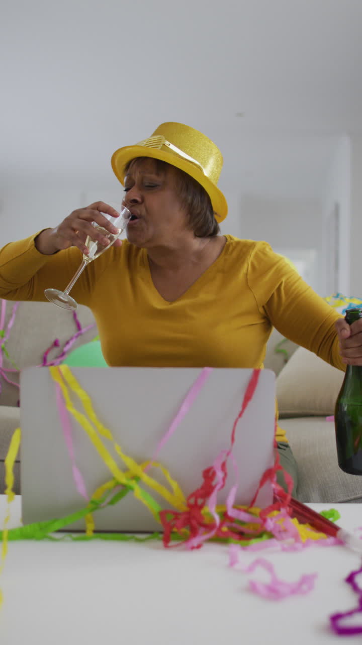 video vertical de una mujer afroamericana mayor celebrando con champán haciendo una llamada de video portátil