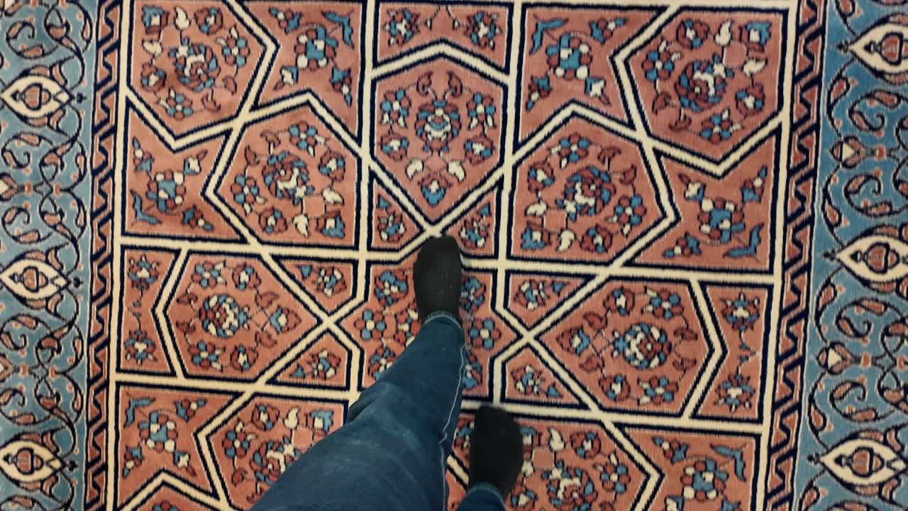 Person's Feet on an Ornate Geometric and Floral Patterned Rug
