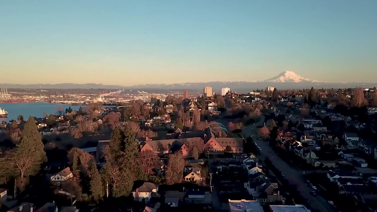 수평선에 산이 있는 석양의 평화로운 해안가 동네의 하강 공중 샷
