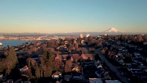 Descending-aerial-shot-of-a-peaceful-waterfront-neighborhood-at-sunset-with-a-mountain-on-the-horizon