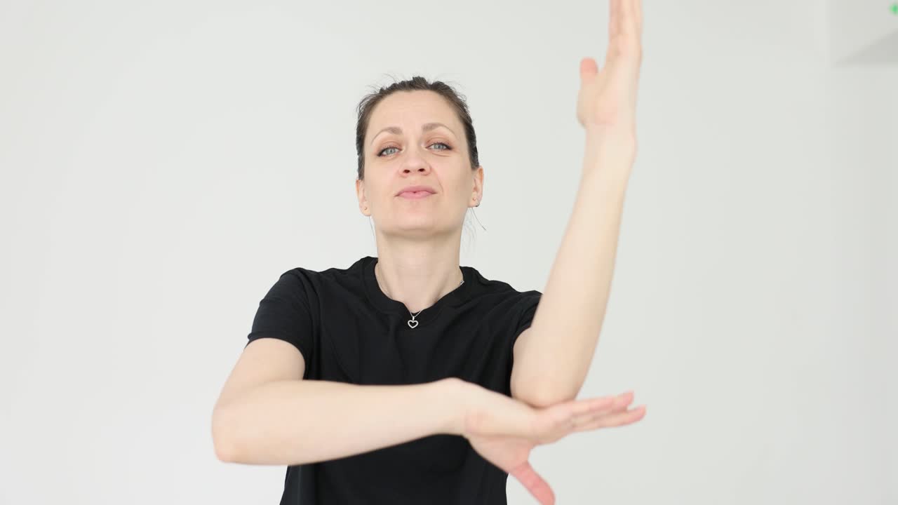 Woman demonstrating arm movements against a white background