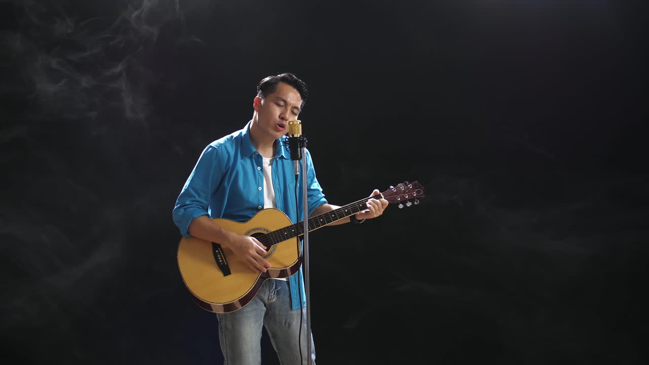 hombre cantando y tocando la guitarra acústica en el escenario