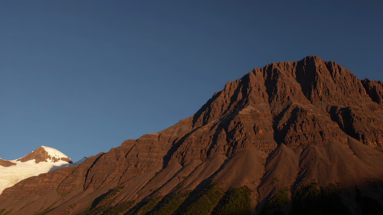 Majestic Rugged Mountain Range with Snow-Capped Peak Under Clear Blue Sky