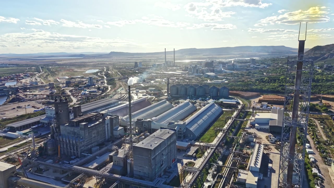 View of an industrial area with factories, storage buildings, and transportation lines in a vast landscape during the day