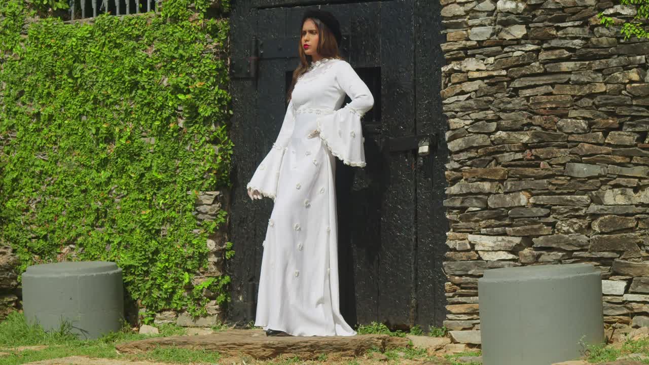 A young girl in a traditional wedding dress from a bygone era, standing on a fort.