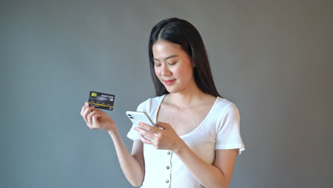 Young-beautiful-Asian-woman-using-smartphone-with-hand-holding-credit-card