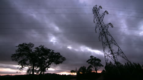 silhouette of electricity pylon against dramatic sunset sky