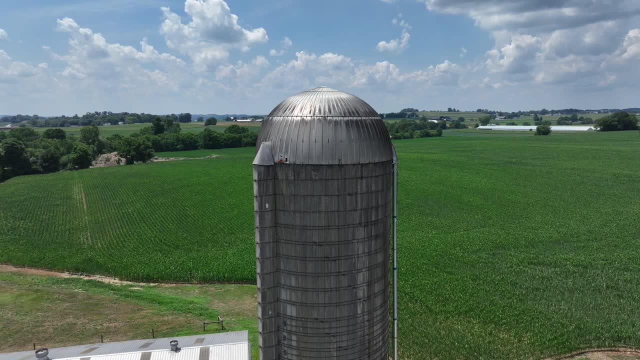 fotografía aérea de un silo de almacenamiento en una granja rodeada de campos verdes y árboles en verano