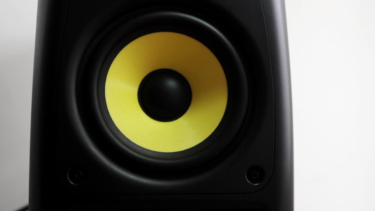 Vooraanzicht close-up van een trillende subwoofer met geel membraan.