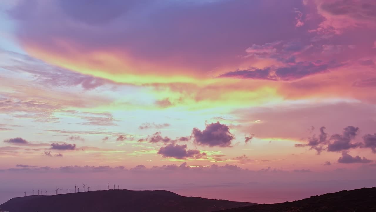 Espectacular cielo al atardecer de color rosa y púrpura con aerogeneradores sobre el océano