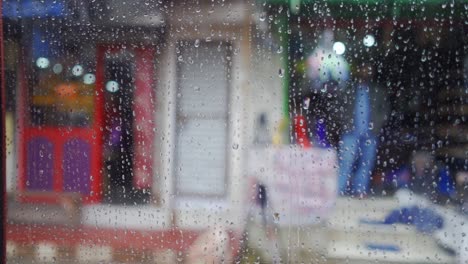 Vista-Desde-El-Interior-De-La-Ventana-Del-Auto-En-Un-Día-Lluvioso,-Rostros-Borrosos-De-Personas-Y-Lugares,-Gotas-De-Lluvia-En-Cámara-Lenta-Sobre-El-Vidrio