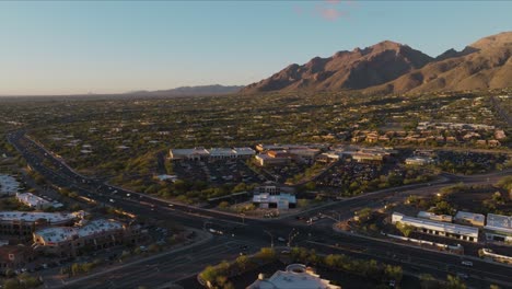 imagen de un dron volando sobre una concurrida intersección de tucson, el tráfico se mueve rápidamente en la hora pico en las estribaciones de catalina, montañas en el fondo con coches debajo