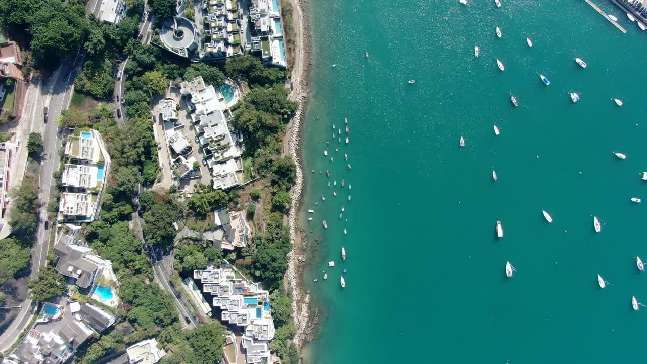 Strada costiera della baia di Hong Kong con traffico e acqua turchese calma, vista aerea