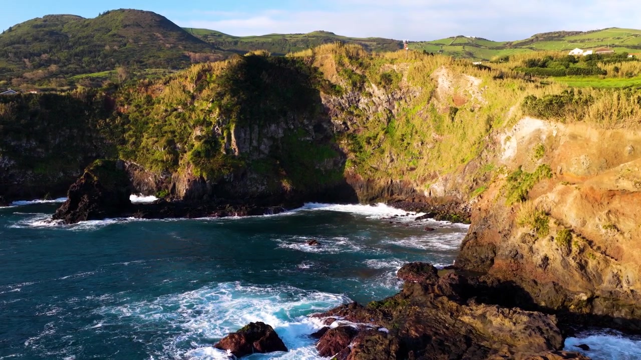 Mostra la frastagliata costa vulcanica dell'isola di Flores nelle Azzorre, Portogallo, con scogliere rocciose e l'Oceano Atlantico. Ripresa aerea laterale