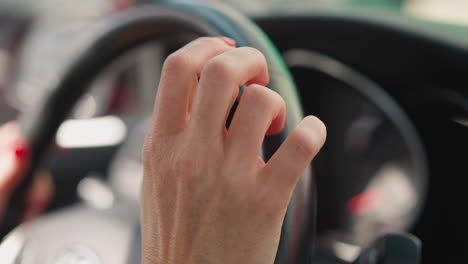 female hands with red manicure hold steering wheel of car