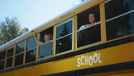 Two-multiethnic-pupils-looking-out-school-bus-window.-Teenagers-ready-to-studies