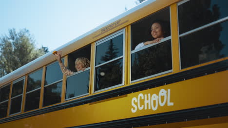 two multiethnic pupils looking out school bus window. teenagers ready to studies