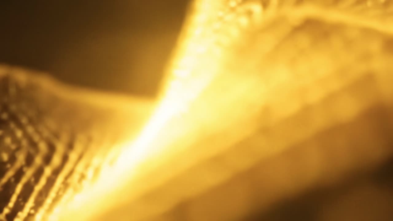 Captivating light displays move fluidly across textured backgrounds, creating a mesmerizing visual experience with warm golden tones. Perfect for relaxation or focus.
