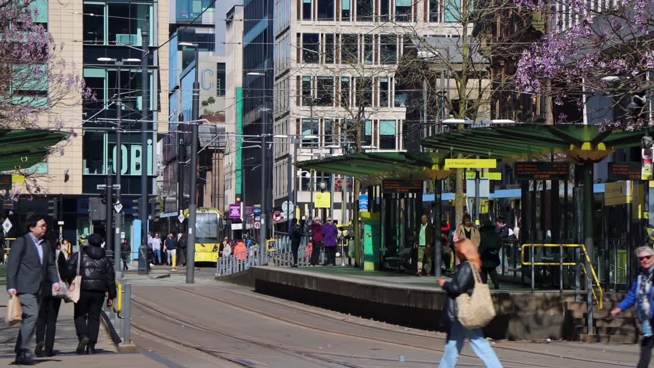 People walk by tram station at St. Peter’s Square in Manchester on busy spring day
