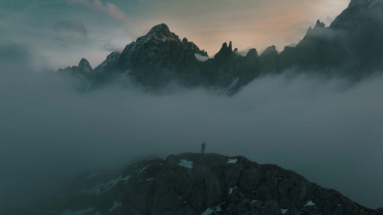 Hombre de pie frente a un valle cubierto de nubes y una montaña revelada. Dolomitas italianos del Tirol del Sur. Ambiente místico.